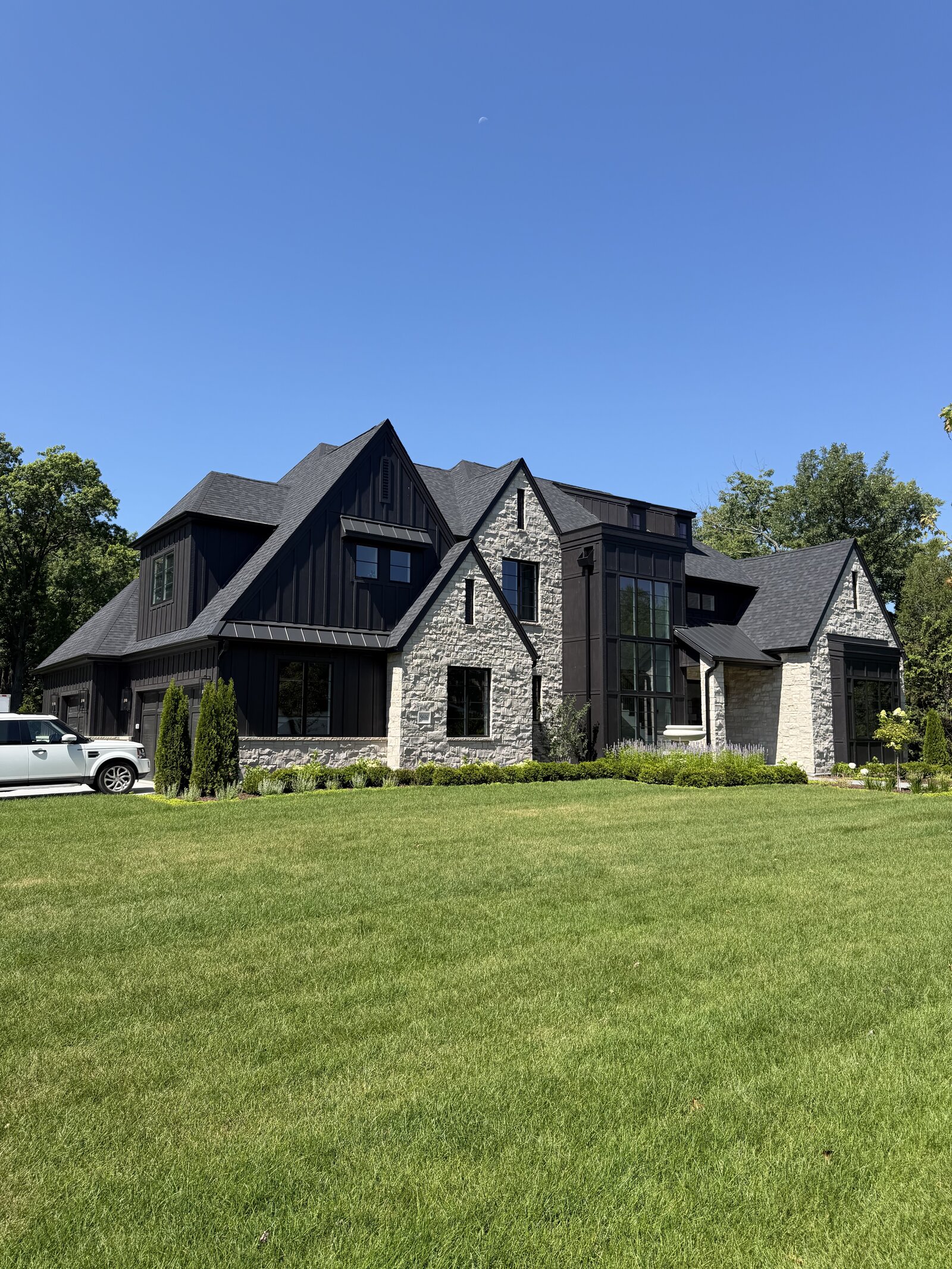 Modern Tudor custom home by Spyglass with black board-and-batten siding and white limestone in Chicago's southwest suburbs