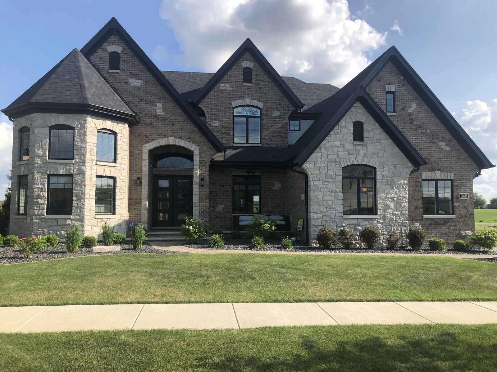 French country custom home with stone turret, arched entry, brick and limestone exterior built by Spyglass