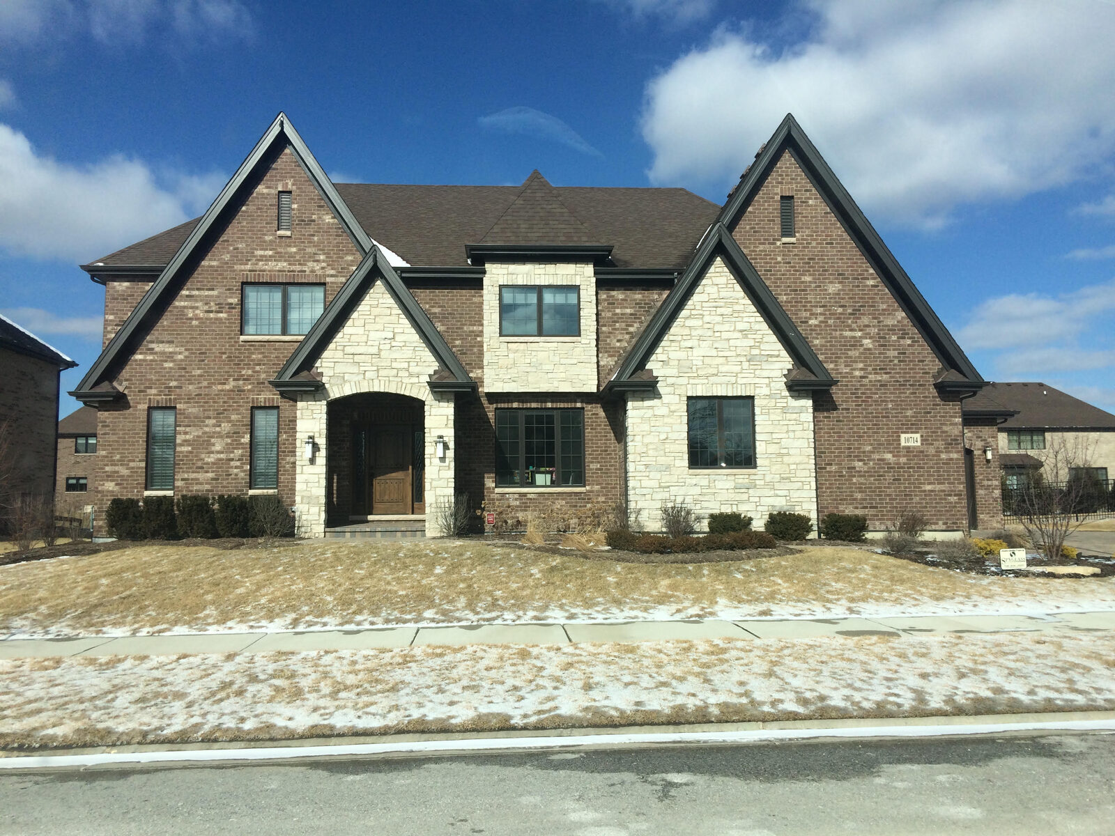 Brick Tudor custom home with stone-accented gables, arched stone entry surround and a central stone tower built by Spyglass