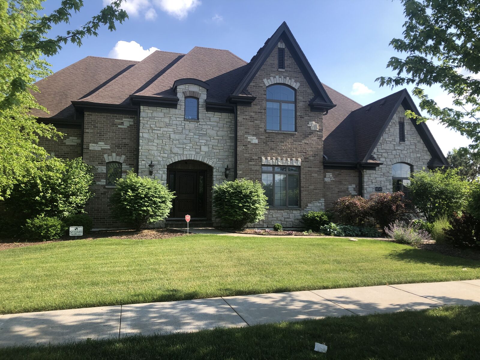 Brick and limestone Tudor custom home with arched entry and diamond-pane accent windows built by Spyglass