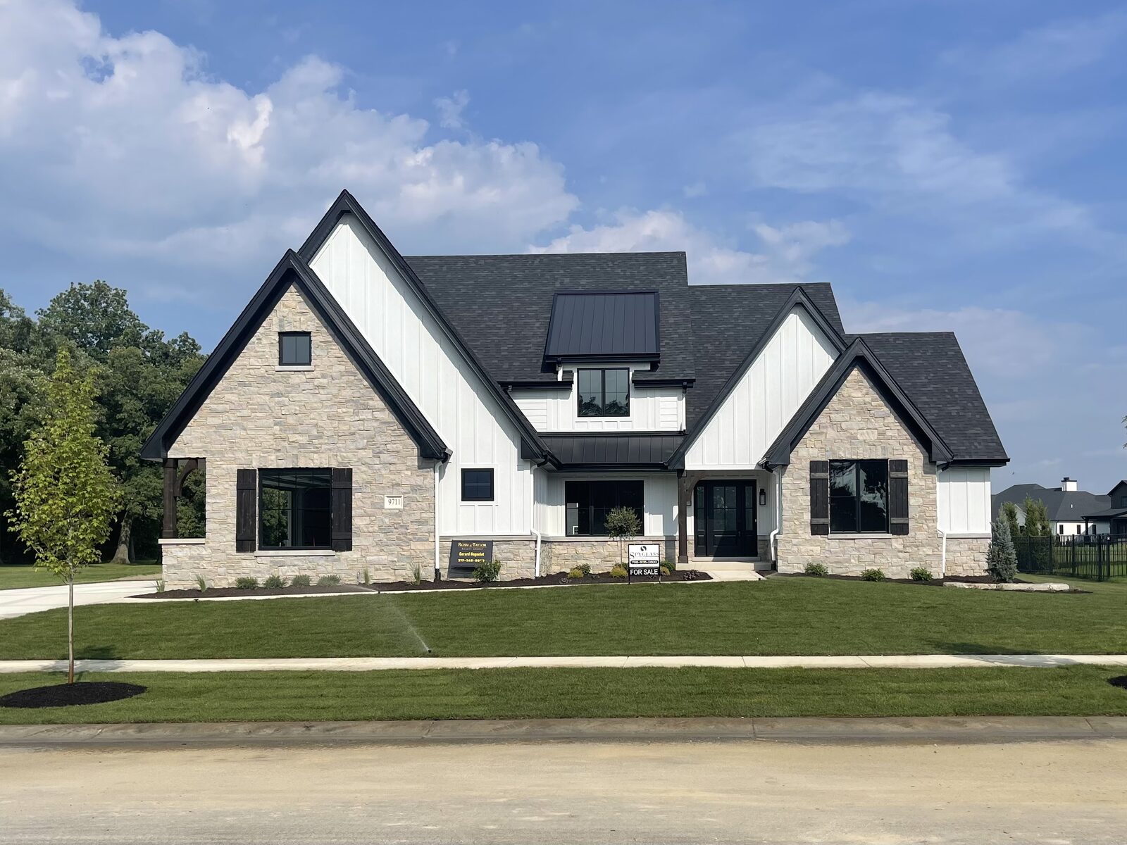 White modern farmhouse custom home with stone gable accents, black shutters and a covered timber porch built by Spyglass